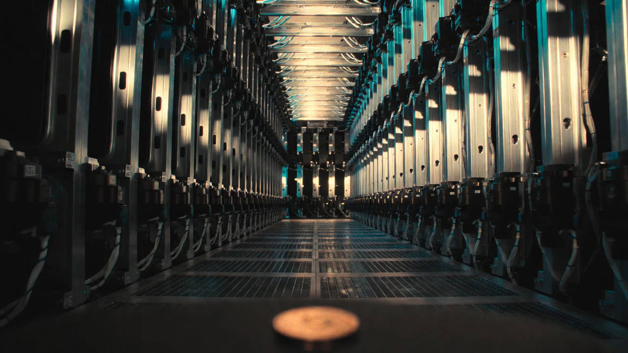 Economia delle macchine: corridoio di server rack con moneta fisica sul pavimento.