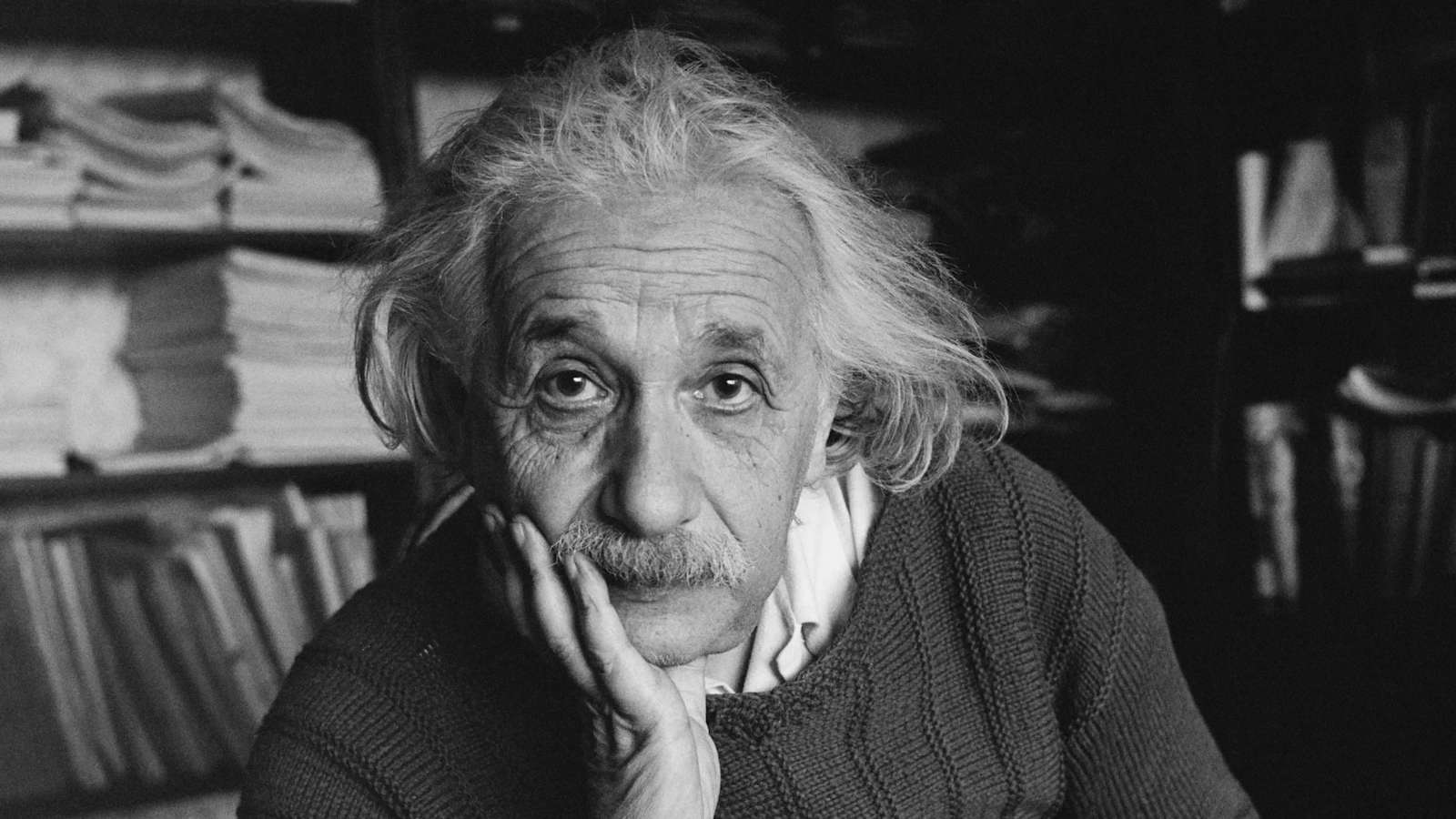 Il Dio di Spinoza: biblioteca vuota con scaffali geometrici e un libro aperto sotto una luce calda